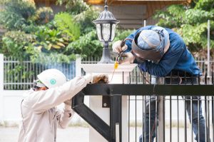 Two workers installing a wrought iron fence in Frisco